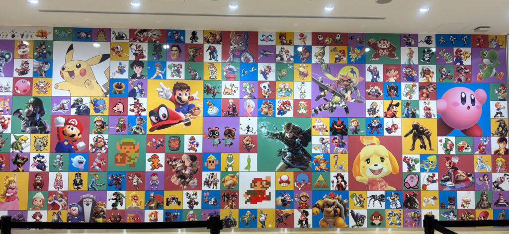 ニンテンドーミュージアムの展示エリアの壁面に描かれた、ピカチュウ、マリオ、リンク、カービィなど多くの任天堂キャラクターが集合したイラスト